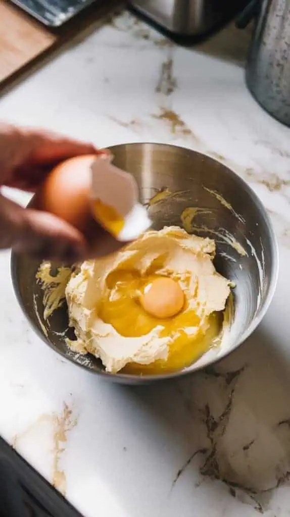  the bowl with the butter mixture and a cracked egg being added.