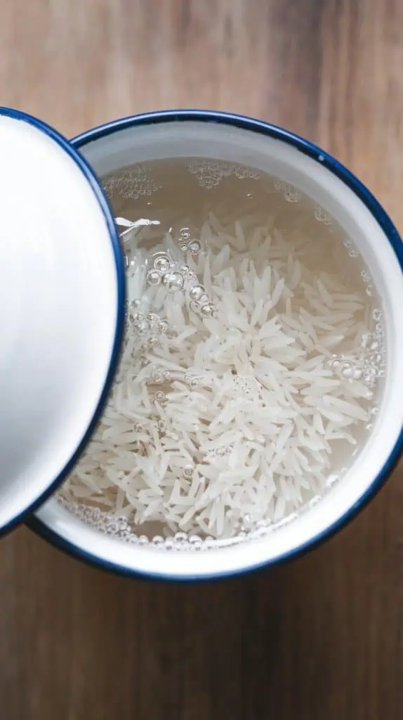 A super close-up, top-down shot of a covered bowl with white rice soaking in water