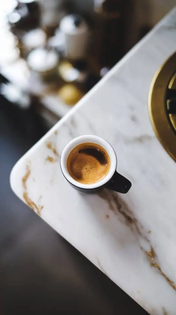 a freshly brewed espresso shot in a small white cup. The coffee is dark and rich, with a golden crema on top