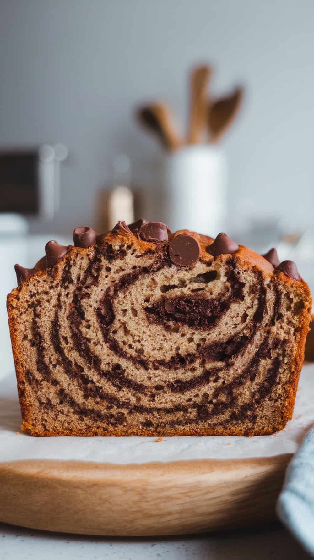 A loaf of chocolate chip cinnamon swirl banana bread on a wooden board