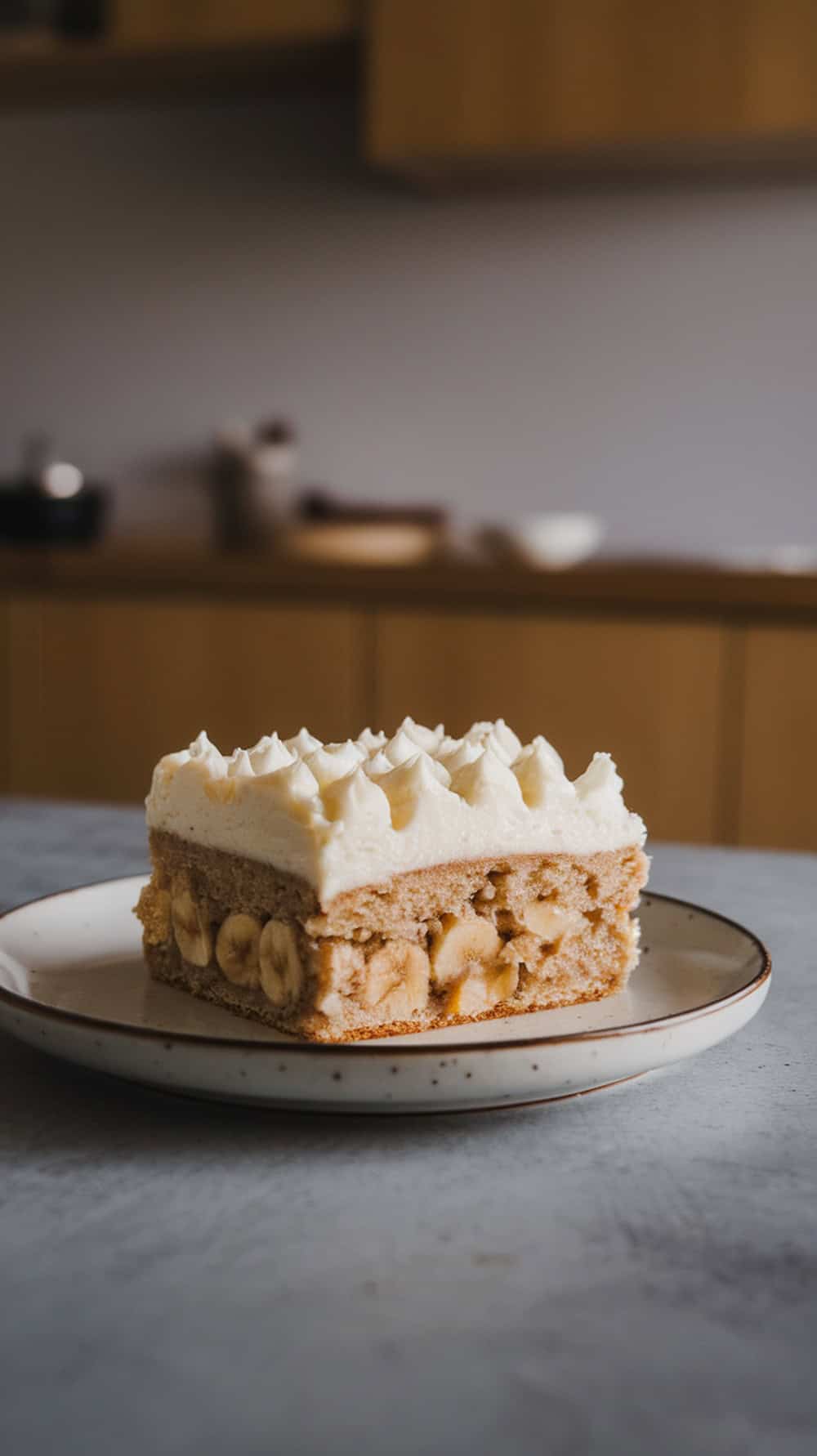 Close-up of banana bars with cream cheese frosting on a plate.