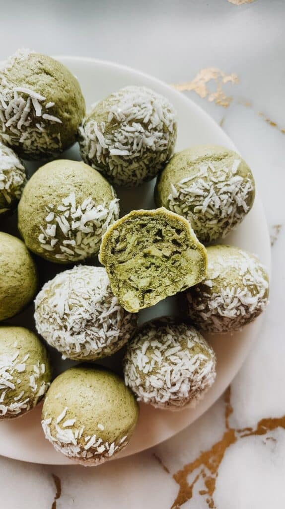 matcha coconut protein balls arranged on a white plate, with a dusting of shredded coconut