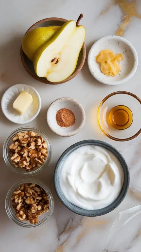 ginger pear yogurt bowl ingredients: peeled and sliced ripe pear on a small ceramic plate, fresh grated ginger on a tiny plate, ground cinnamon on a small dish, a pat of butter on a plate, honey drizzled onto a glass plate, thick Greek yogurt in a shallow dish, and optional toppings—chopped walnuts and granola—in small clear jars