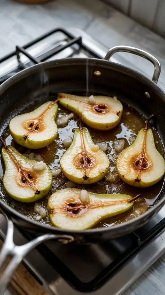 pear slices sizzling in melted butter in a skillet, coated with grated ginger, cinnamon, and honey